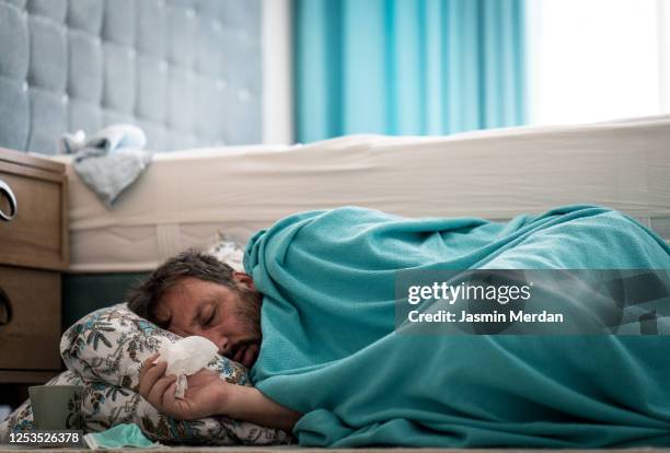 sick man with fever on ground in bedroom - man flu foto e immagini stock