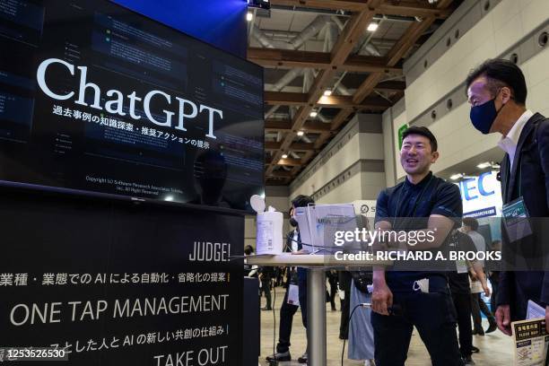 Man speaks with a booth representative next to a digital display promoting ChatGPT, a hugely popular language app that has sparked a rush in...