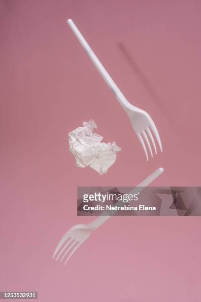 white disposable forks in flight on a pink background. garbage. - plastic cutlery stock pictures, royalty-free photos & images