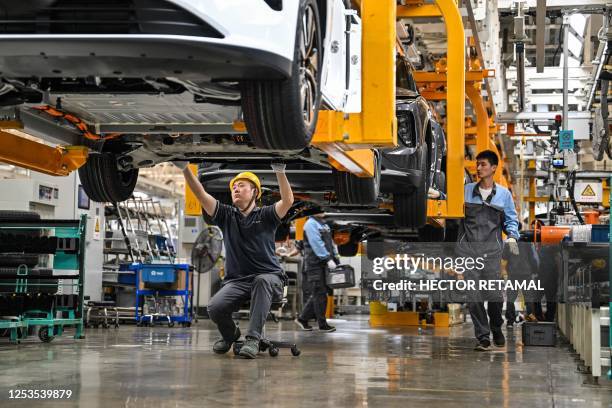 An employee checks under a car along the assembly line at a factory of Chinese automaker NIO in Hefei, in China's eastern Anhui province on May 10,...