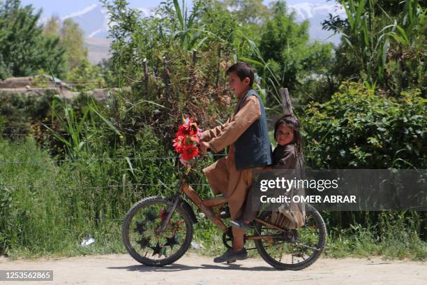 Boy with a girl ride a bicycle along a road in Argo district of Badakhshan province on May 10, 2023.