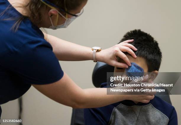 Orthoptist Angela Dillon, left, places a patch over Noah Garcia's eye as he prepares him for an eye test during his appointment at Houston Eye...