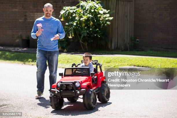 Travis Oglesby smiles after art dealer Hiram Butler gave him the a bunch of sweet pea blossoms as he walked past Butler's house, with his son, Finn,...