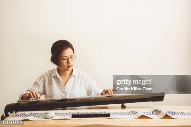 asian woman playing the guqin (an ancient chinese string musical instrument) - plucking an instrument foto e immagini stock