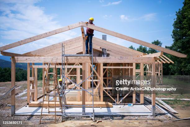 trabajadores de la construcción que trabajan en el techo de madera de la casa. - construction frame fotografías e imágenes de stock