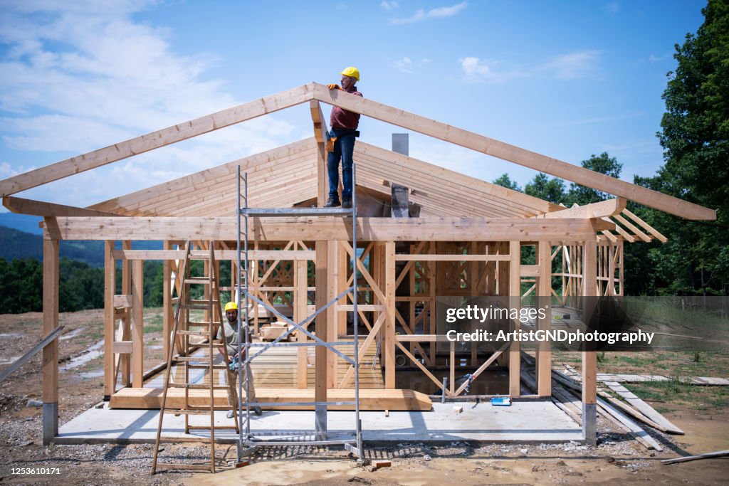 Ouvriers de construction travaillant sur le toit en bois de la maison.