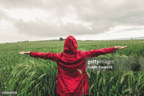 mujer con impermeable rojo bajo la lluvia - tormenta tiempo atmosférico fotografías e imágenes de stock