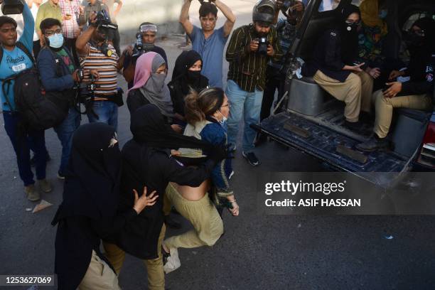 Women police personnel detain a protester as Pakistan Tehreek-e-Insaf party activists and supporters of former Pakistan's Prime Minister Imran Khan...