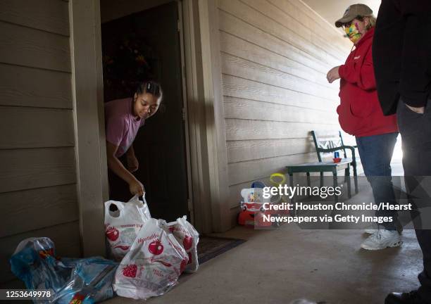 Briana Jones, left, picks up a bag of food delivered to her by Crowdsource Rescue's Terri Hackl Saturday, Feb. 20, 2021 in Spring. The volunteer...