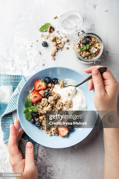 healthy food homemade granola with nuts mix, yogurt and honey on blue plate in female hands for breakfast, top view. - fibra foto e immagini stock