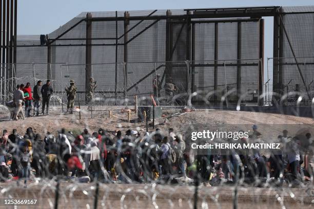 Migrant people wait on the banks of the Rio Grande to be processed by the Border Patrol El Paso Sector, Texas, after crossing from Ciudad Juarez,...