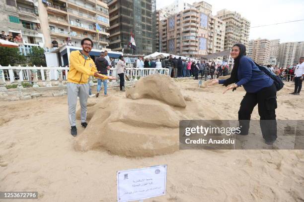 Students of faculty of fine arts pose for a photo with sand sculpture as they compete during Sand Sculpture Festival in Alexandria, Egypt on May 10,...