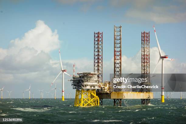 episk utsikt över stora offshore 8mw vindkraftverk, vindkraftpark vid horisonten i nordsjön med jack up båt och offshore plattform i vågigt hav - oljeplattform bildbanksfoton och bilder