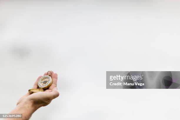 a man's hand holds a compass with the sky - norte imagens e fotografias de stock