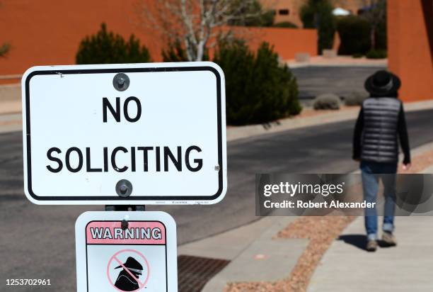 Resident enters her condominium complex walking past No Soliciting and Neighborhood Watch signs in Santa Fe, New Mexico.