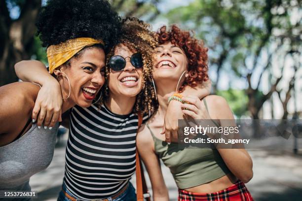 three beautiful ladies hugging in city - female friendship stock pictures, royalty-free photos & images