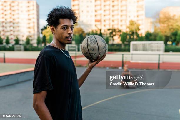 young black man holding basketball - street basketball imagens e fotografias de stock