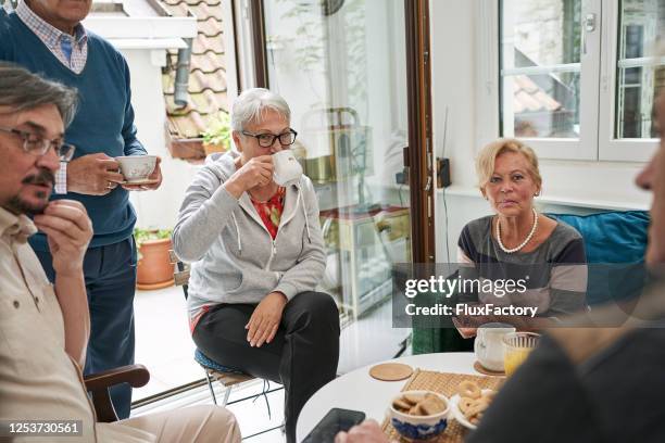 a group of senior people enjoying coffee and talking - community centre stock pictures, royalty-free photos & images