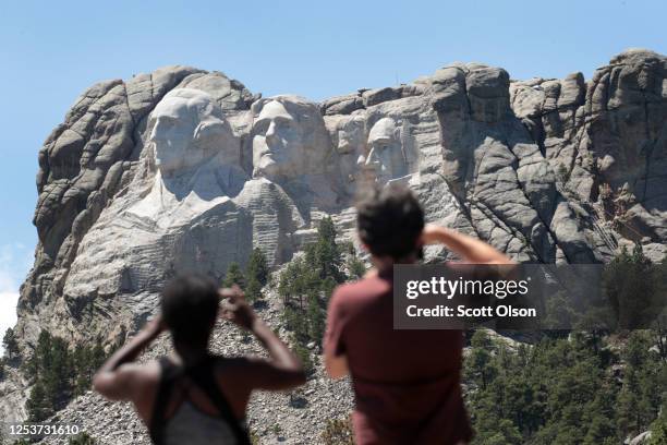 People take photos of U.S. Presidents George Washington, Thomas Jefferson, Theodore Roosevelt and Abraham Lincoln at Mount Rushmore National Monument...