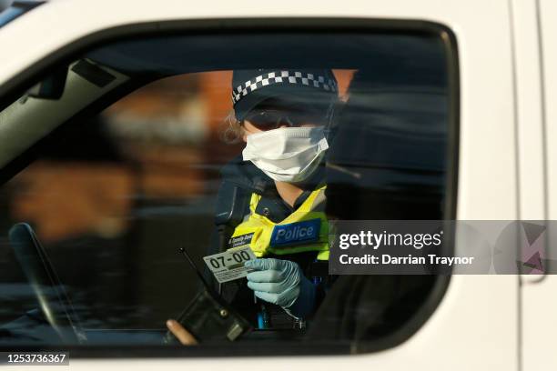 Police check the identification of members of the public at a pop up road block in Broadmeadows to ensure they have legitimate reasons for leaving...