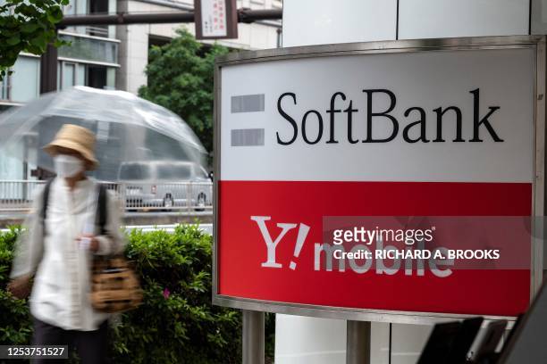 Pedestrian walks past a sign for Japanese company SoftBank and Y!Mobile outside a telecommunications shop in Tokyo on May 11, 2023.
