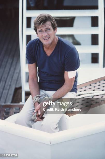 English actor Roger Moore as 007 on the set of the James Bond film 'For Your Eyes Only', February 1981. Here his hands are tied in readiness for a...
