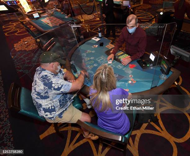 Guests play blackjack at a table installed with plexiglass safety shield dividers and only three seats for social distancing at Mandalay Bay Resort...