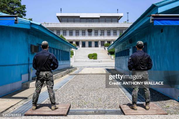 In this photo taken on May 9 South Korean soldiers stand guard as they face North Korea's Panmon Hall at the truce village of Panmunjom in the Joint...