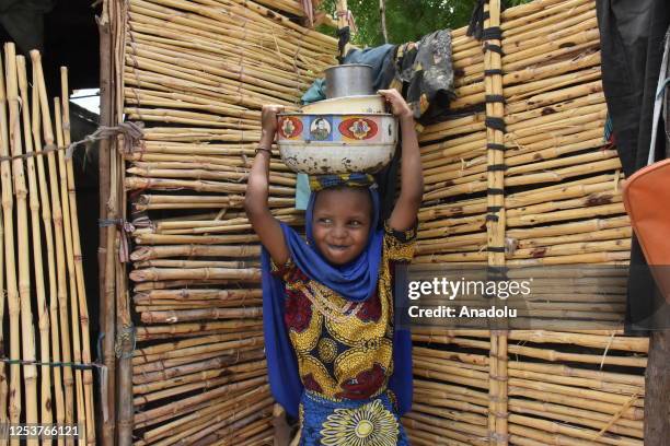 Nigerian child carries buckets of food on their heads at the Gwoza IDP Camp in Borno State, Nigeria on May 03, 2023. While the number of people...