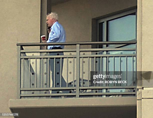 Republican presidential candidate Arizona Senator John McCain stands on the balcony of his residence with a cup of coffee and a mobile telephone, in...
