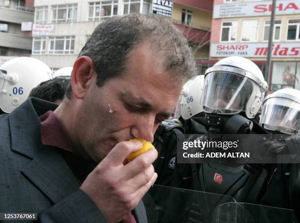 Labourer wipes his face with a lemon to protect himself from the tear gas used by riot police during a protest against the privatization of the State...