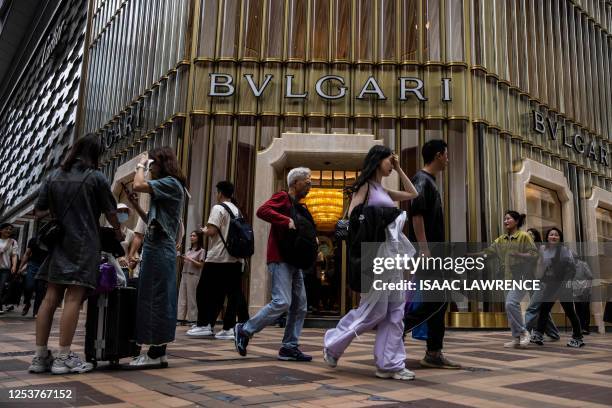 Mainland tourists and pedestrians are seen outside a luxury goods store at a shopping precinct in the Tsim Sha Tsui district of Hong Kong on May 11,...