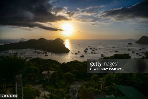 The sun sets in the horizon as ships and boats lower their anchors in Labuan Bajo on May 11, 2023.