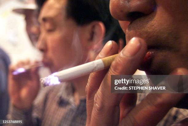 Several men sample the latest Chinese cigarettes 18 June 1999, put on the market by a tabacco company in Yunnan, at a shopping centre in downtown...