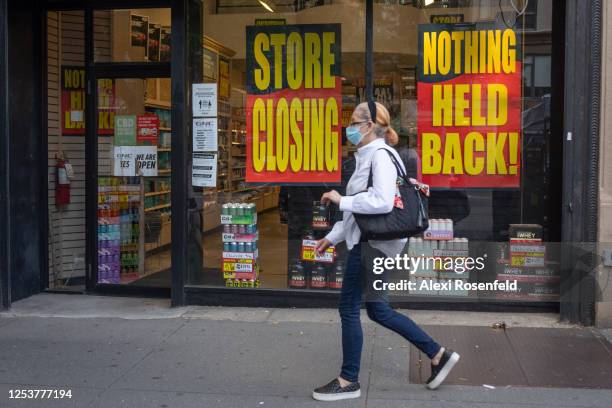 Woman wearing a mask walks past 'Store Closing' and 'Nothing Held Back' signs as the city moves into Phase 2 of re-opening following restrictions...