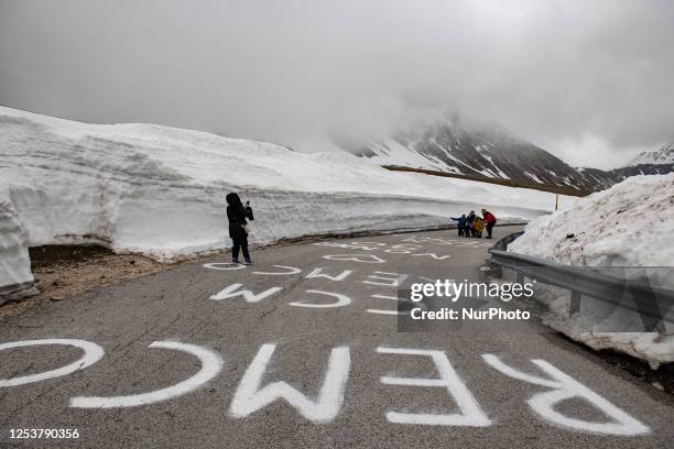 Snow walls, Giro d'Italia messages on the road and a woman taking a picture to a group of people are seen in Campo Imperatore, L'Aquila, on may 11,...