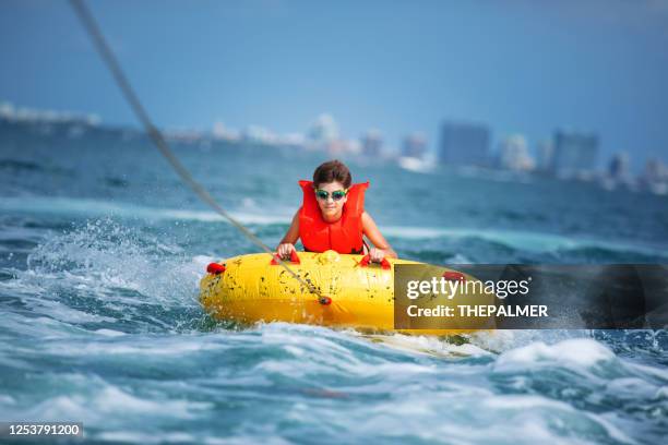 kid riding a yellow tube in miami florida - rubber material stock pictures, royalty-free photos & images