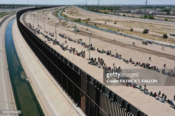 An aerial image shows migrants waiting along the border wall to surrender to US Customs and Border Protection border patrol agents for immigration...