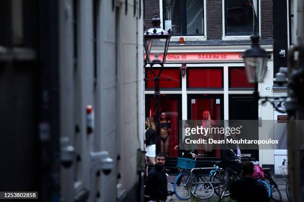 Prostitutes stand behind windows in the Red Light District as it reopens after the Coronavirus or Covid19 Lockdown on July 01, 2020 in Amsterdam,...
