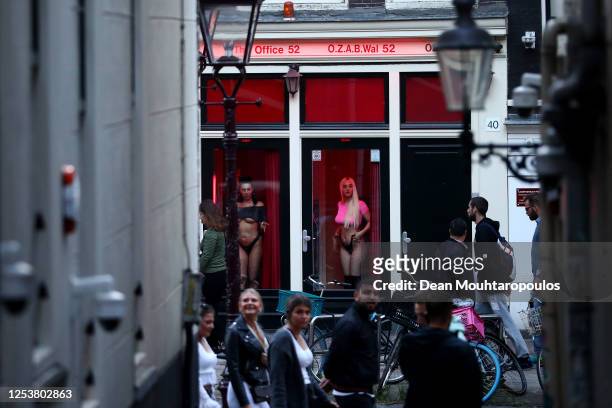 Prostitutes stand behind windows in the Red Light District as it reopens after the Coronavirus or Covid19 Lockdown on July 01, 2020 in Amsterdam,...