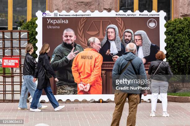 Ukrainians watch an art work presenting President Putin of Russia as a convict displayed on Khreschatyk Street in central Kyiv, the capital of...