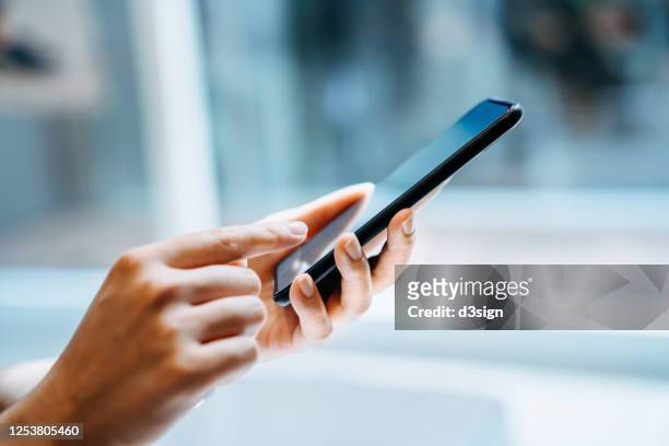 close up of young woman using smartphone at home in sunlight - portable information device stockfoto's en -beelden