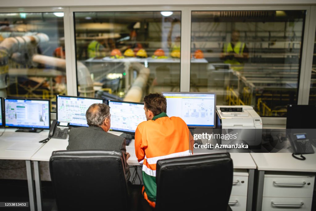 Worker and Manager Sitting in Control Room of Waste Facility
