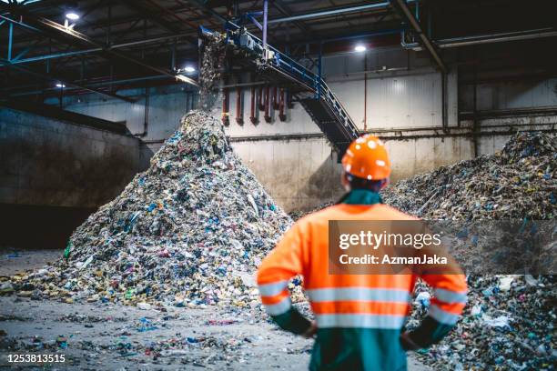 trabalhador observando processamento de resíduos em instalação de reciclagem - plastic - fotografias e filmes do acervo