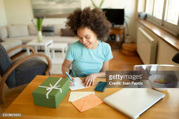 happy african american woman writing a letter - giving tuesday stock pictures, royalty-free photos & images