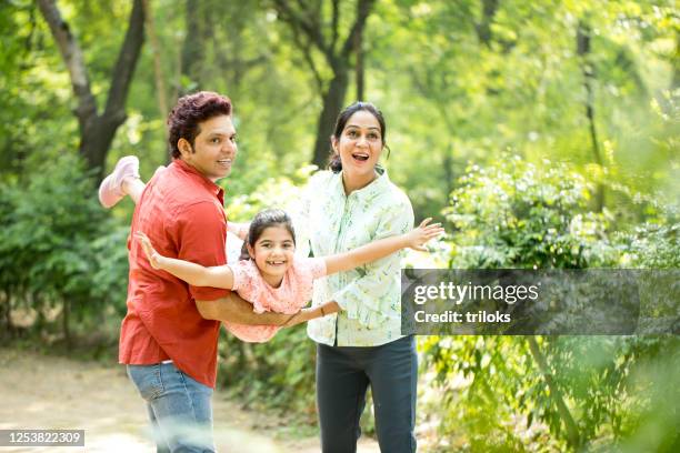 parents lifting daughter and helping her fly - india couple lift stock pictures, royalty-free photos & images