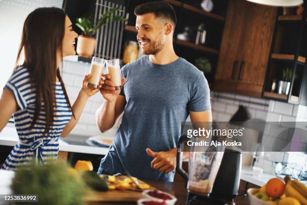 happy couple toasting with juices in the kitchen. - detox diet stock pictures, royalty-free photos & images
