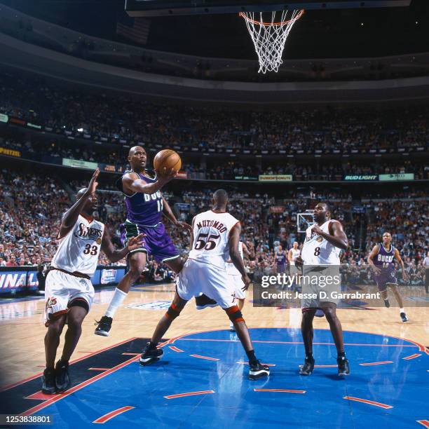 Glenn Robinson of the Milwaukee Bucks shoots against the Dikembe Mutombo and Tyrone Hill of the Philadelphia 76ers in Game one of the 2001 Eastern...