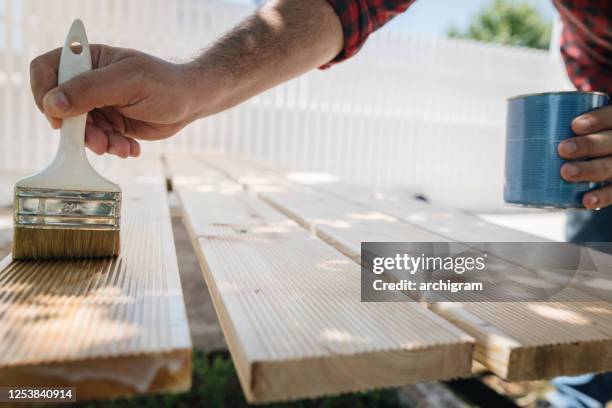 applicare vernice protettiva su una tavola di legno. - garden furniture foto e immagini stock