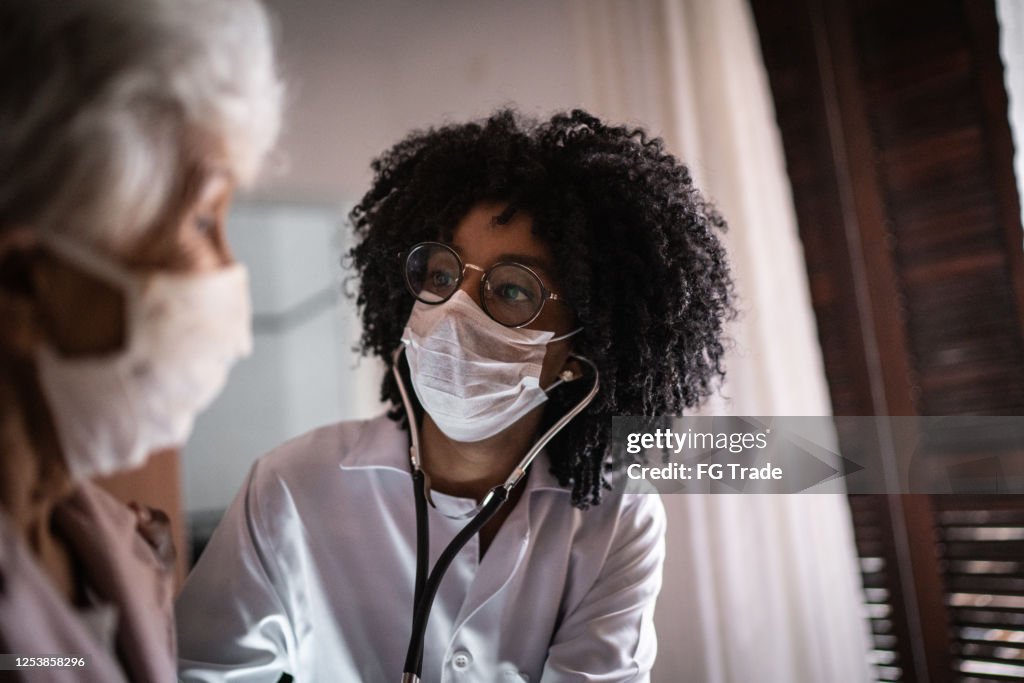 Doctor using stethoscope on a senior patient at home